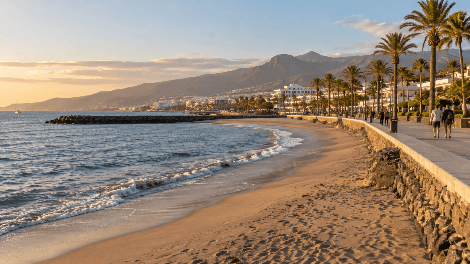 Redaktioneller Blick auf Sandstrand und Promenade in Süd-Teneriffa im Licht des späten Nachmittags.